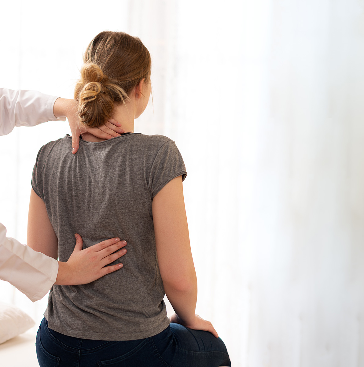chiropractor-feeking-patients-back A female patient sitting upright while a chiropractor evaluates her posture and spine alignment during an initial consultation at Fox and Fern Chiropractic in Bemidji, MN.
